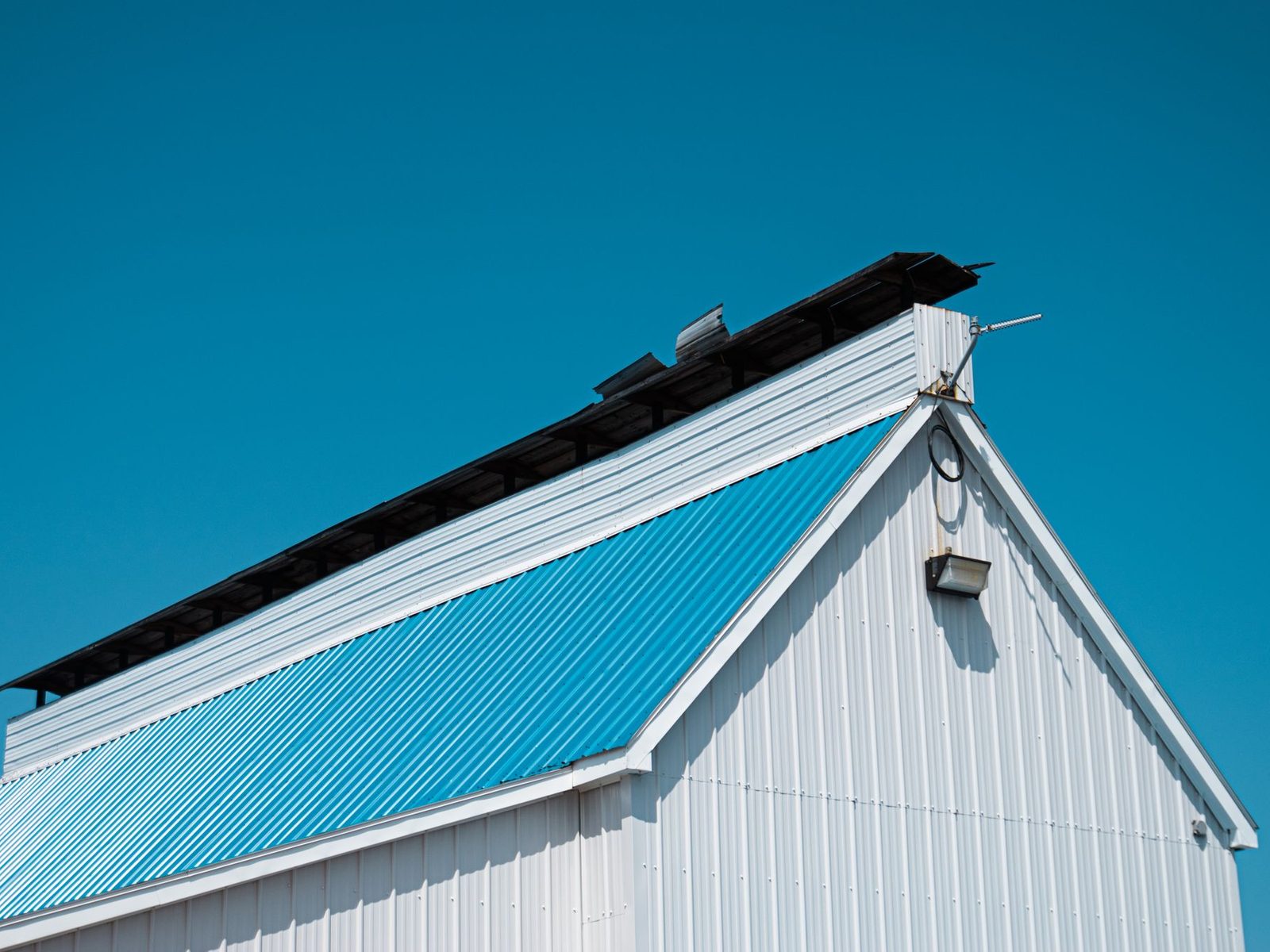 Blue corrugated metal roof on a white metal-clad building
